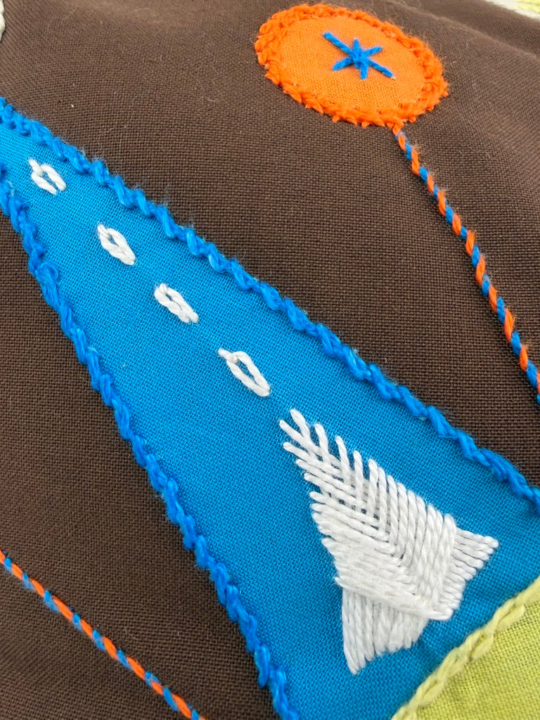 Sol Azul Design by Pamela Nelson. Hand Embroidered Pillow on dark brown Pamela Nelson