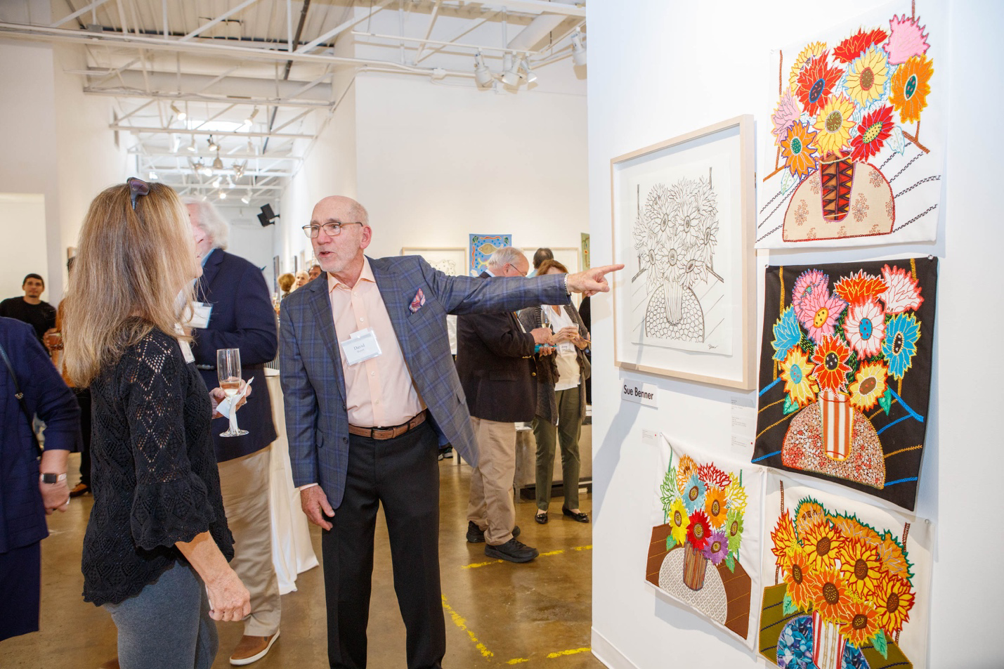 People at an art gallery event with floral artwork on display