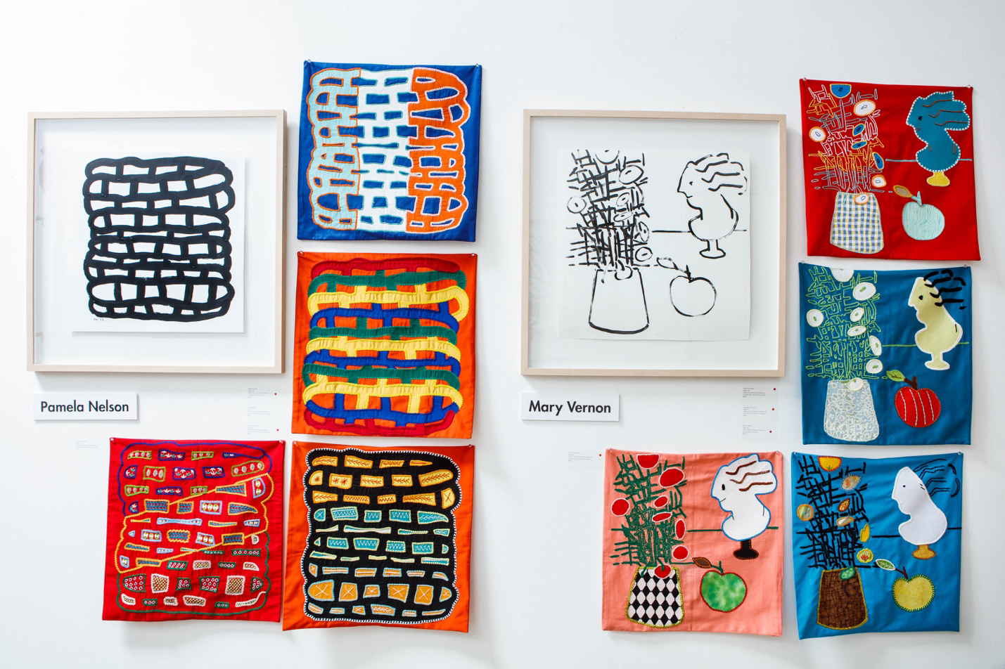 Collection of colorful artworks on a white wall, featuring various patterns and designs.