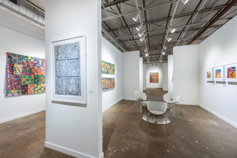 Art gallery with various artworks on white walls and a wooden floor.