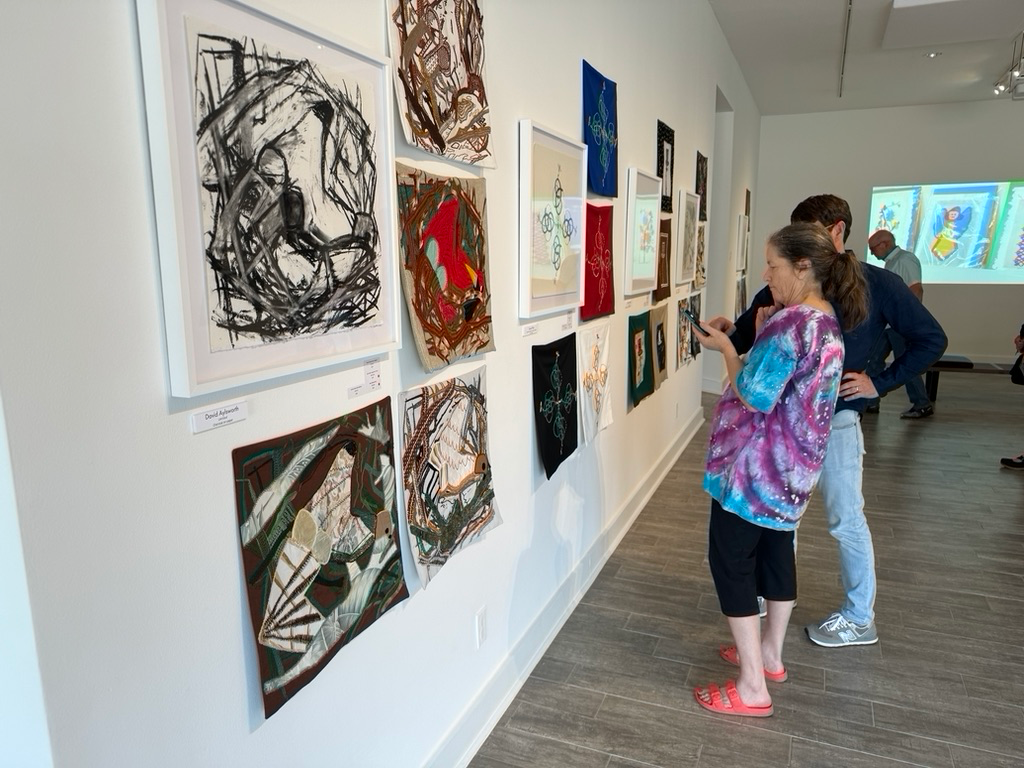Art gallery with visitors looking at artwork on the wall.
